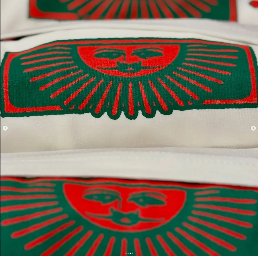 Nahaufnahme eines rot-grünen Sonnengesicht-Motivs auf hellem Stoff